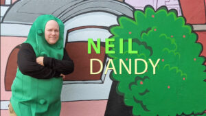 Neil Dandy posing in a pickle suit