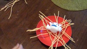 closeup of yeti balanced on top of the spaghetti while a noodle strand is being pulled away