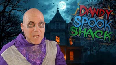 necro neil dandy in front of a haunted house with the dandy spook shack logo