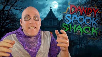 necro neil dandy in front of a haunted house with the dandy spook shack logo