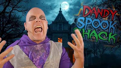 necro neil dandy in front of a haunted house with the dandy spook shack logo