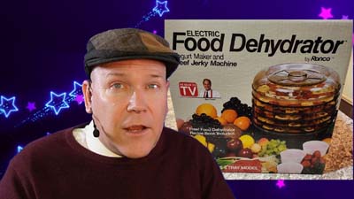 neil dandy with a picture of the ronco electric food dehydrator packaging
