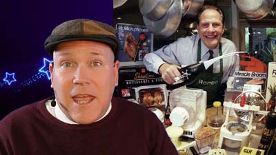 neil dandy with a picture of ron popeil showing off a variety of kitchen gadgets