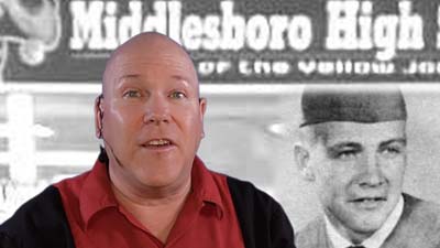 neil dandy with picture of lee majors in cap and gown in front of middlesboro high school banner